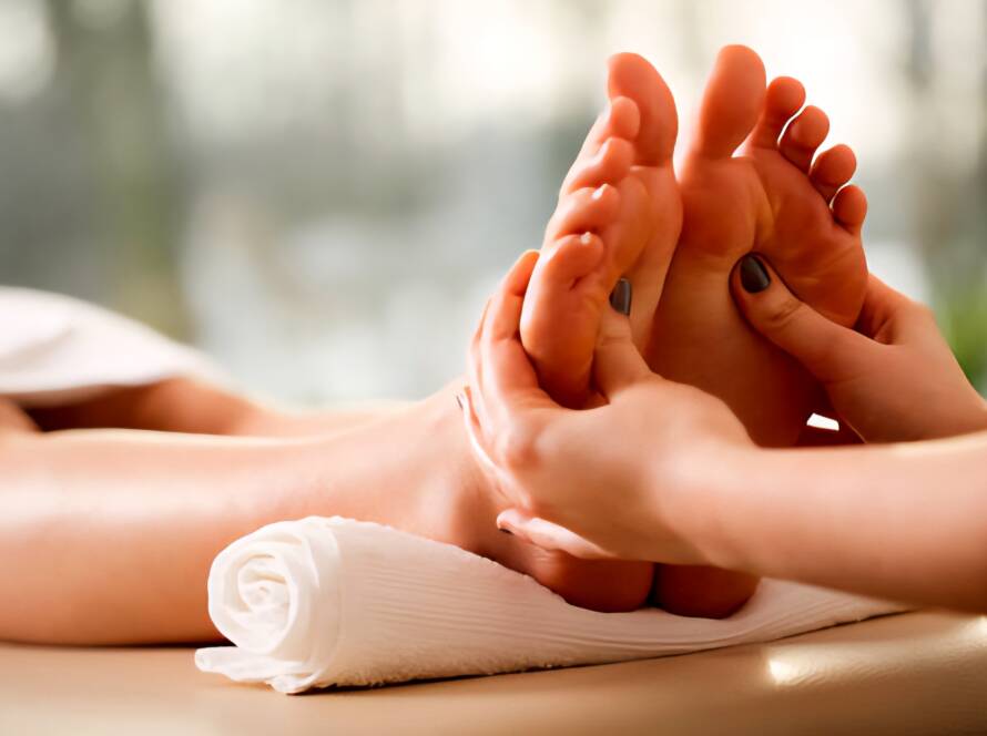Reflexology massage therapist applying gentle pressure to a client’s feet at Rowan and Peridot Collective in Lethbridge