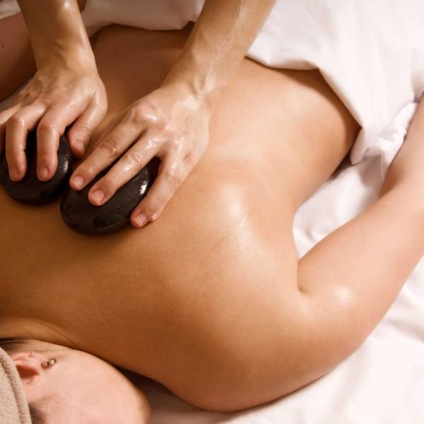 lose-up view of smooth, heated stones on a client’s back during Hot Stone Massage therapy