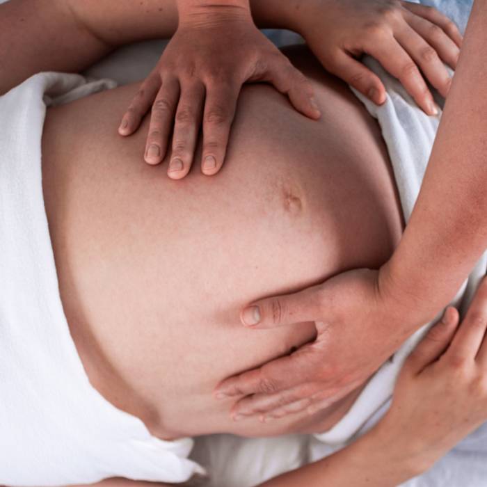 Pregnant client receiving a prenatal massage on her lower back at Rowan and Peridot Collective in Lethbridge