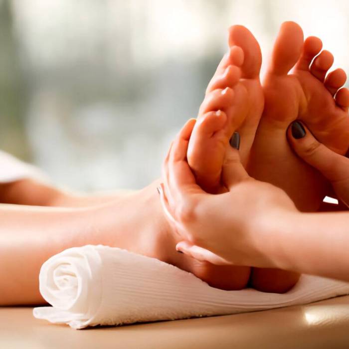Reflexology massage therapist applying gentle pressure to a client’s feet at Rowan and Peridot Collective in Lethbridge
